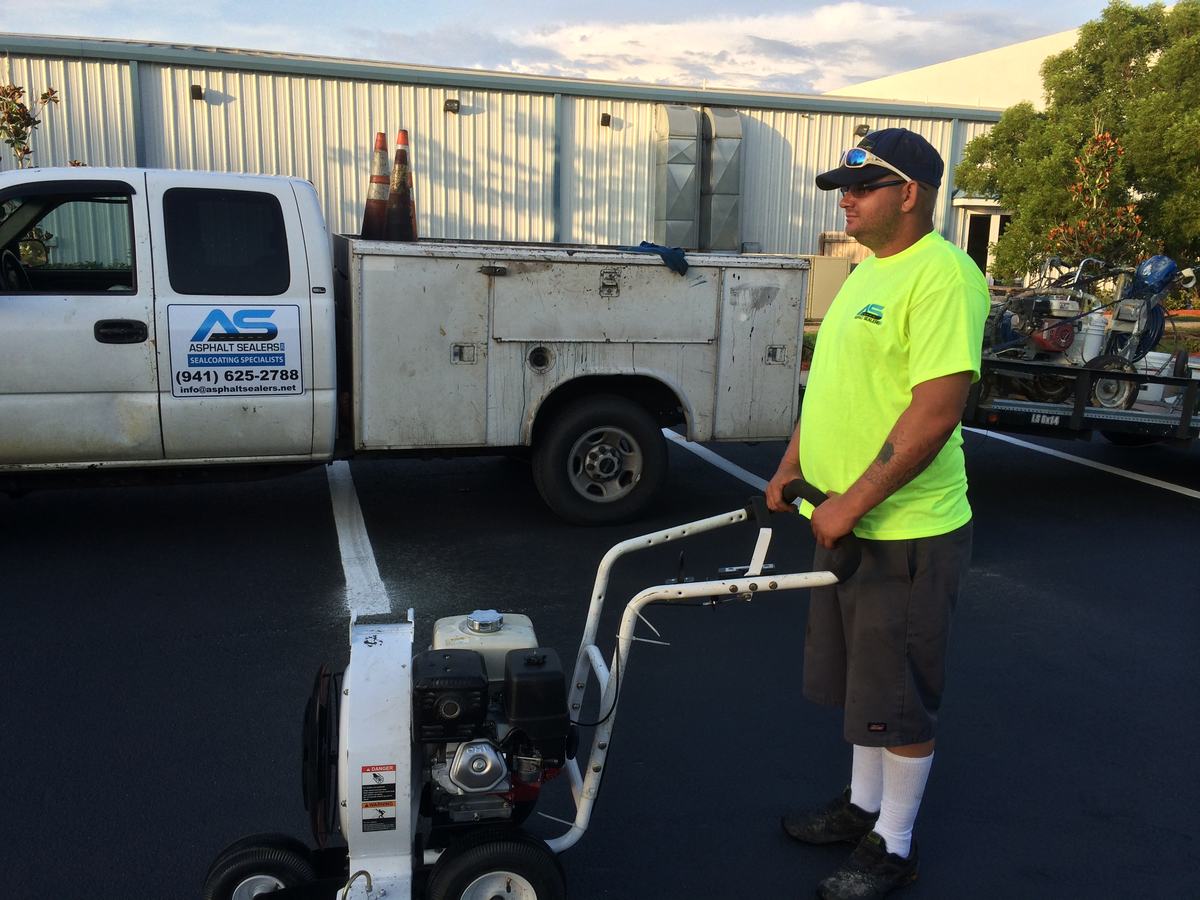 Asphalt Services crew member with equipment and company truck