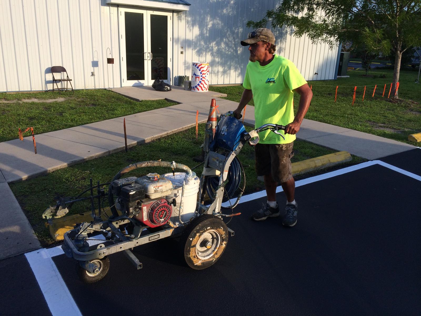 Crew member with a line striper beside a building